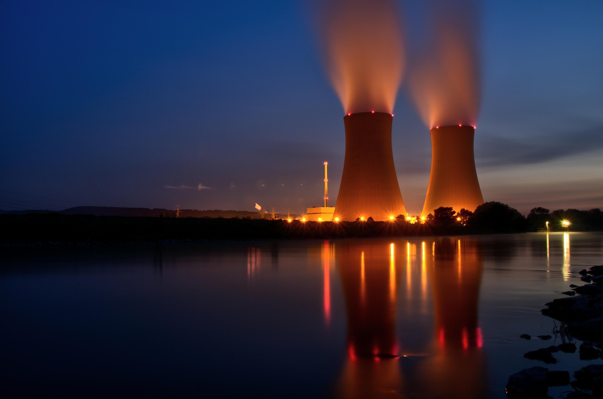 Energy power plant behind body of water at night
