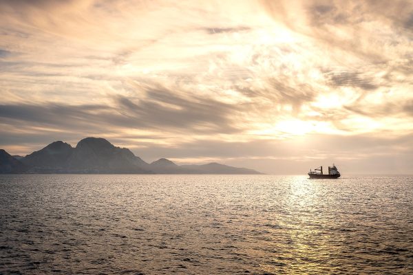 Boat traveling through sea straight mountains in distance
