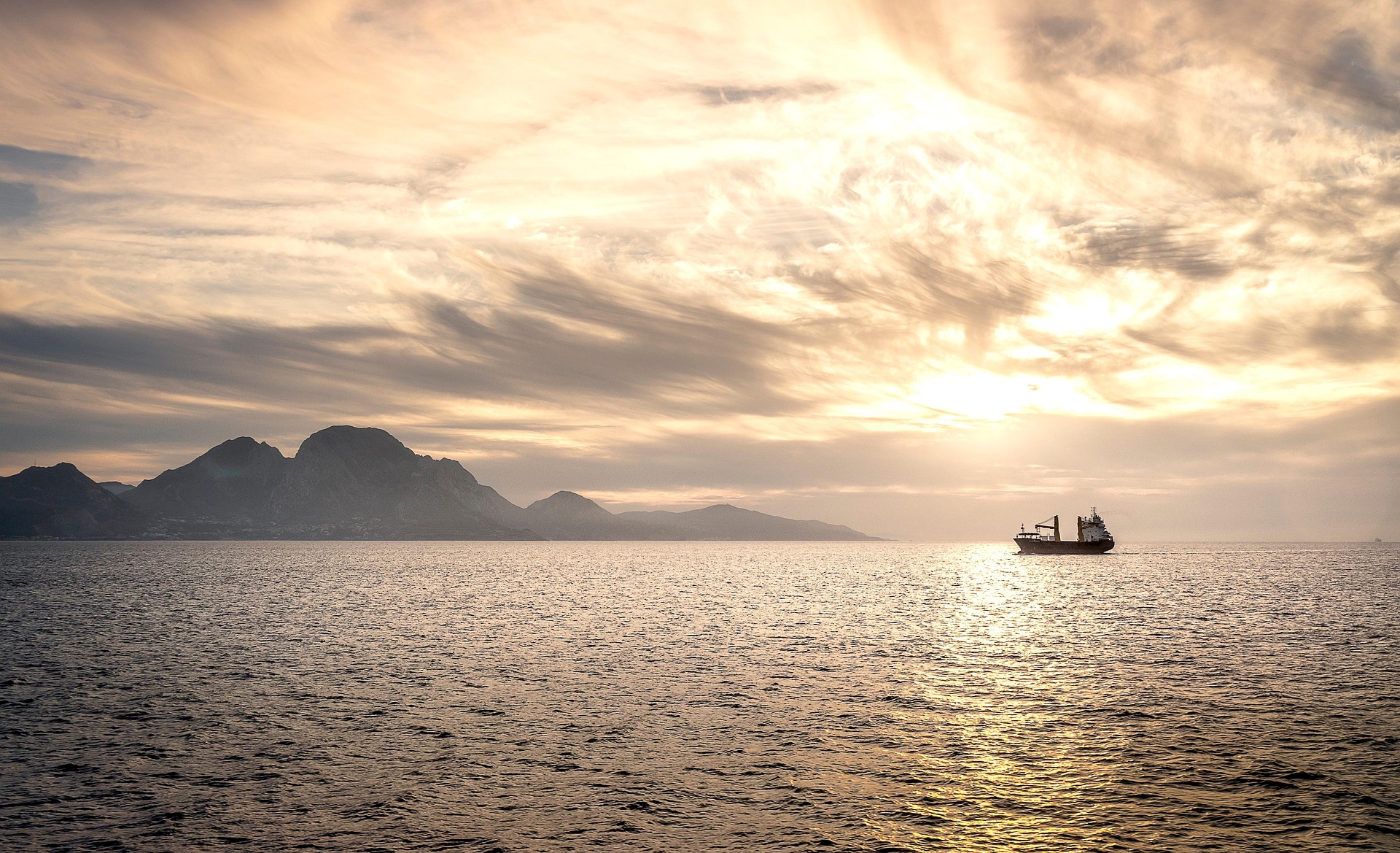 Boat traveling through sea straight mountains in distance