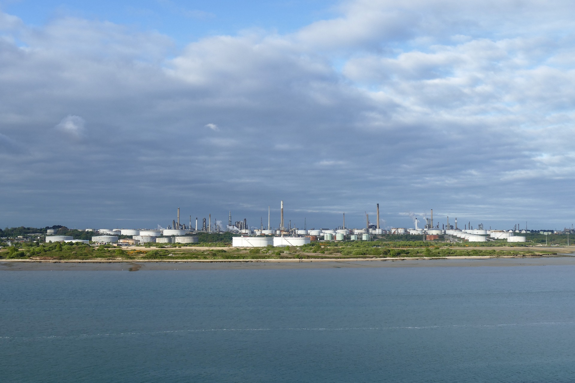 Large oil refinery in distance next to body of water