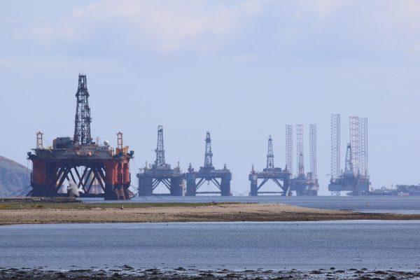 Oil rigs in sea with shore in foreground