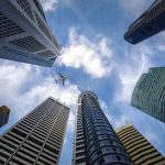 Singapore skyscrapers as seen from street view with plane overhead