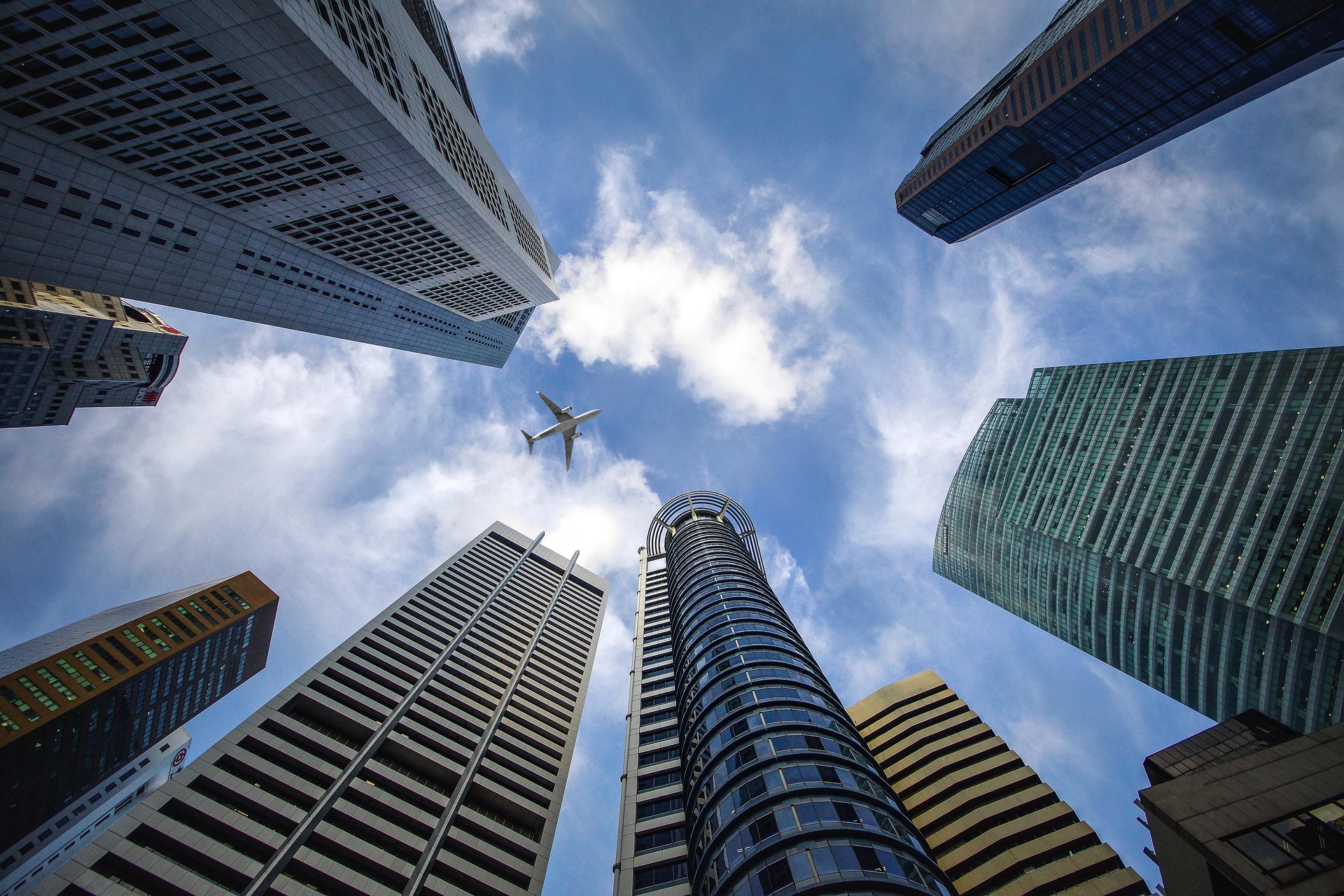 Singapore skyscrapers as seen from street view with plane overhead