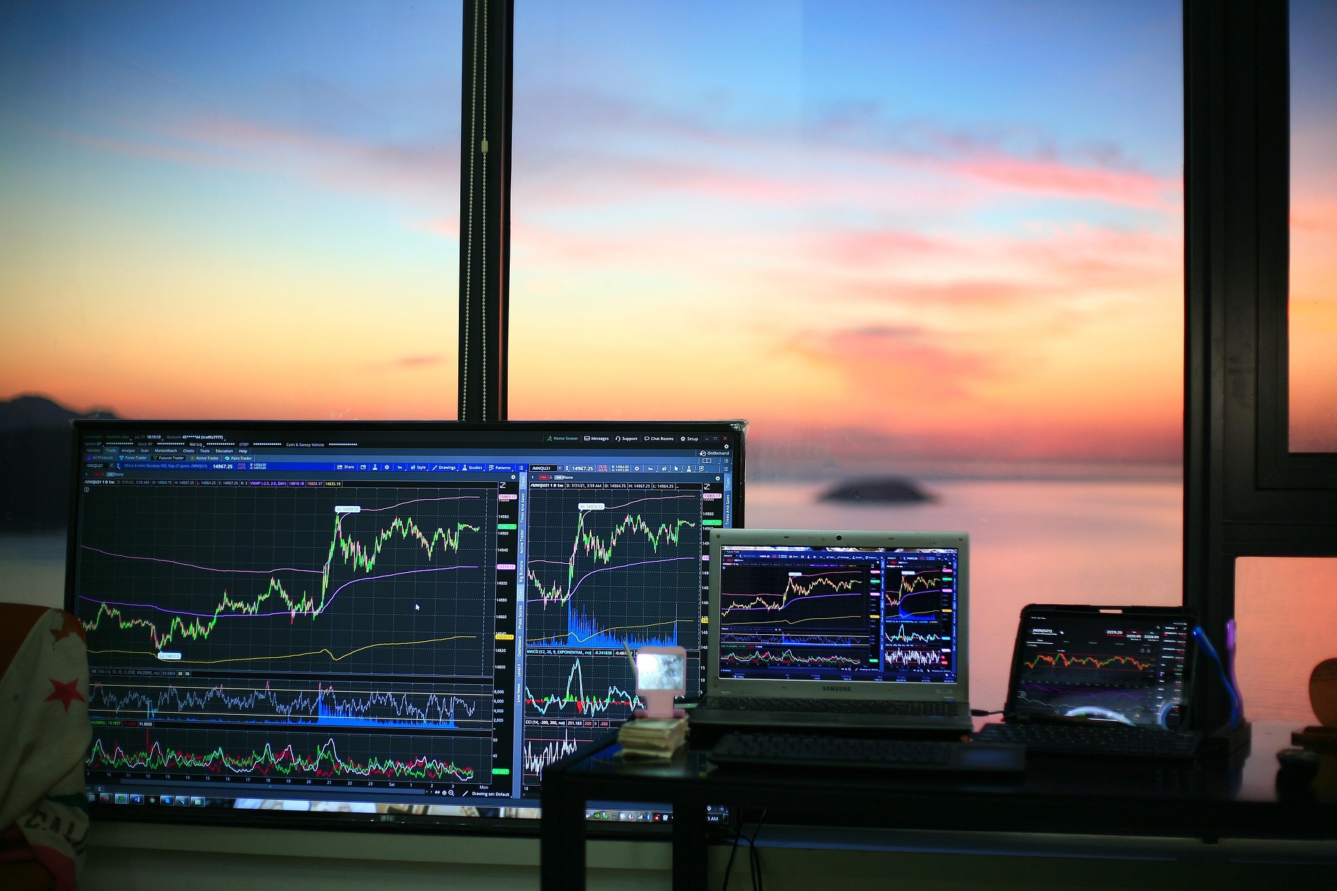 Three screens monitoring stocks in front of office window