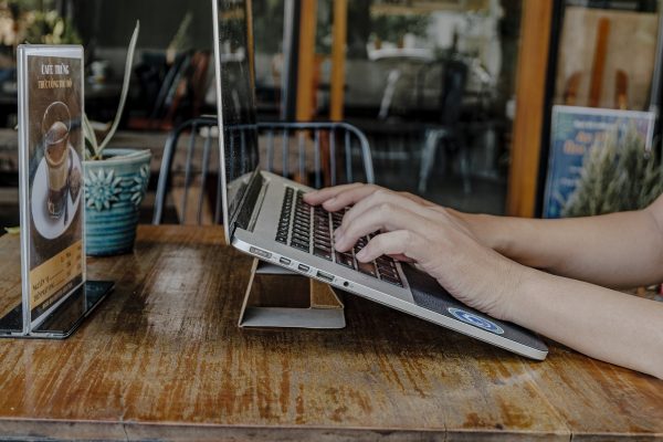 human working on propped up laptop in cafe