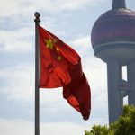 China flag on pole in front of skyscraper